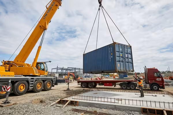 Flatbed truck with crane placing a shipping container